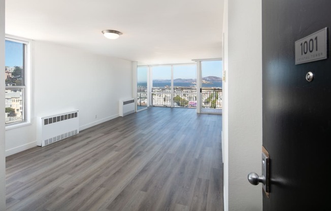 an open living room with hardwood floors and a balcony