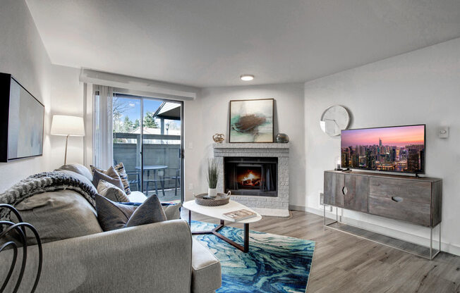 a living room with a fireplace and a sliding glass door to a balcony