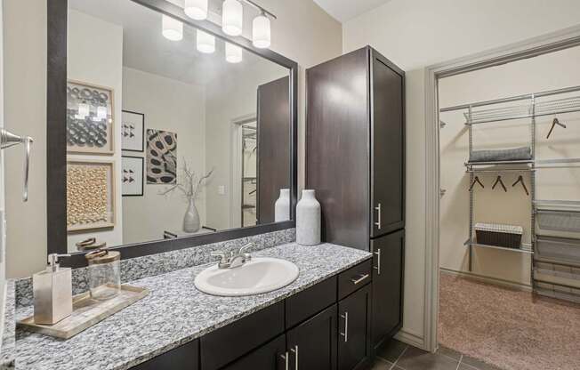 A bathroom with a sink, mirror, and cabinets.