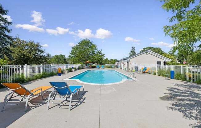 A pool surrounded by chairs and trees.