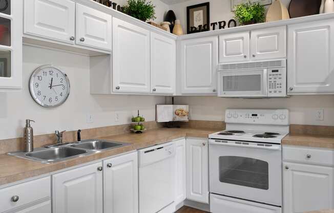 a kitchen with white cabinets and appliances and a clock