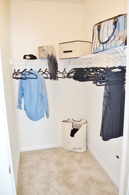 Walk-in closet with racks with hangers; top shelf for storage