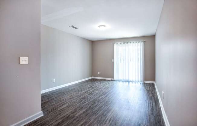 an empty living room with wood flooring and a window