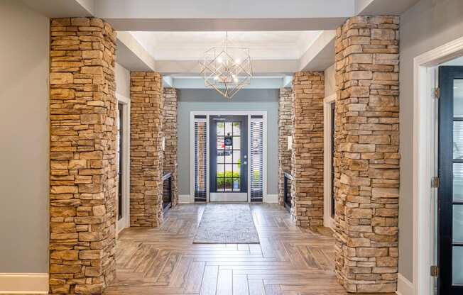 the lobby of a house with stone columns and a chandelier