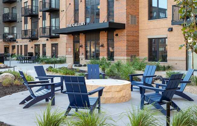 a firepit with adirondack chairs in front of a building at The Gallery Apartments, Minnesota