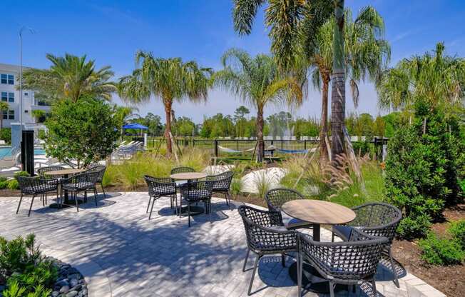 a patio with tables and chairs and palm treesat Altis Grand Lake Willis, Orlando Florida