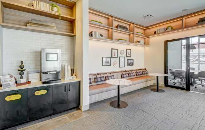 a room with a coffee machine and a table with a book shelf in the background