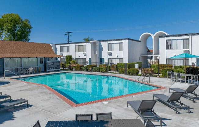 a swimming pool with chairs around it in front of a buildingat The Arches Apartments, LLC, El Cajon