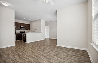 an empty living room and kitchen with white walls and wood flooring