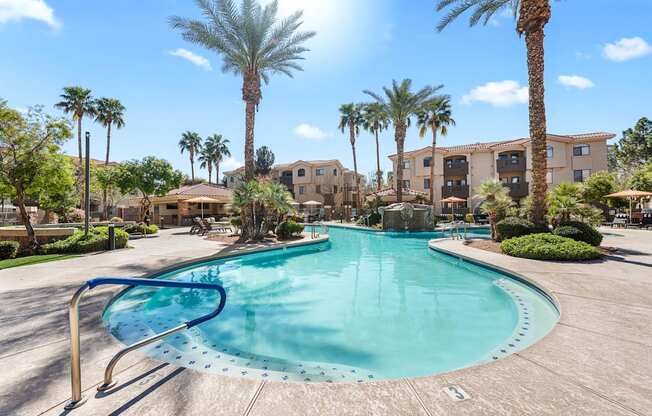 A large swimming pool surrounded by palm trees and apartment buildings.