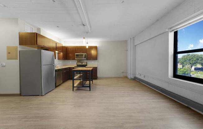 A kitchen with a refrigerator, microwave, and a table with a chair.