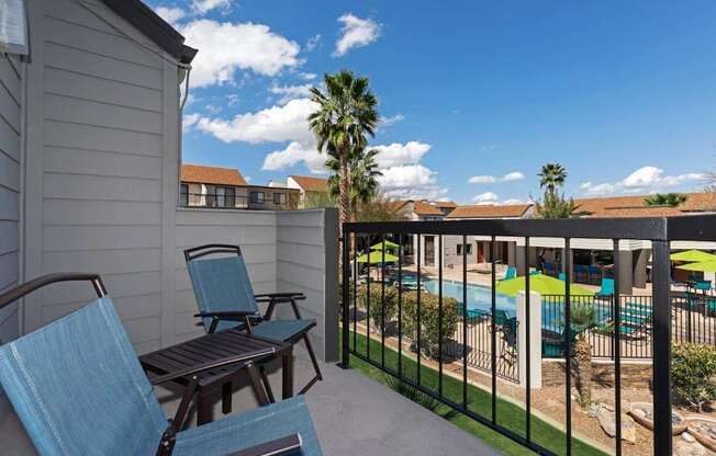 A patio with chairs and a pool in the background.
