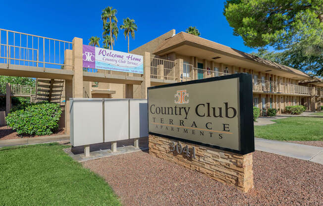 A sign for the Country Club Terrace Apartments stands in front of a building.