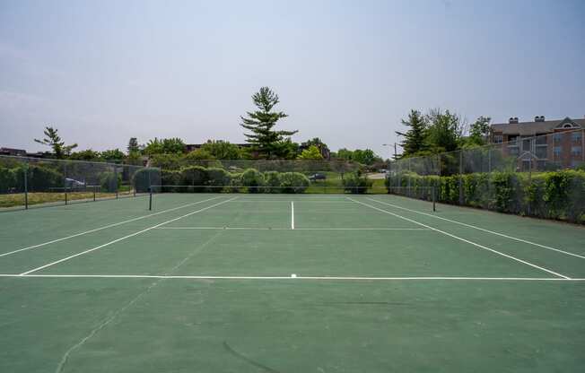 a tennis court with trees and buildings in the background