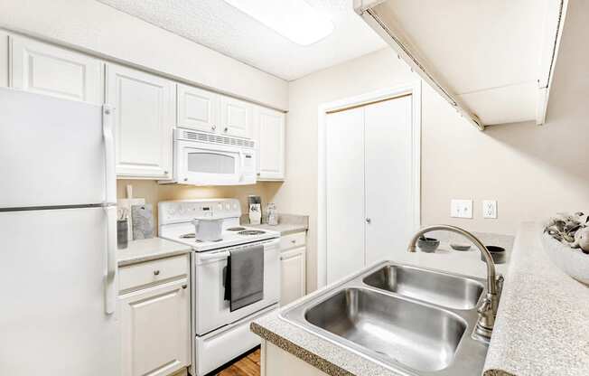 Virtually staged kitchen with granite inspired countertops, white appliances, white cabinetry, double basin sink, pot on stove and cutting boards