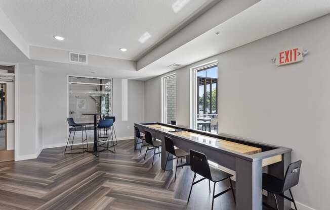 a game room with a shuffleboard table and chairs
