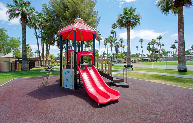 a playground with a red slide and monkey bars