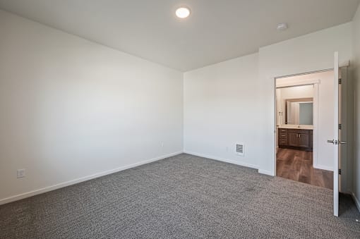 a bedroom with white walls and carpet and a door to a bathroom at Gateway Apartments, Washington, 98802