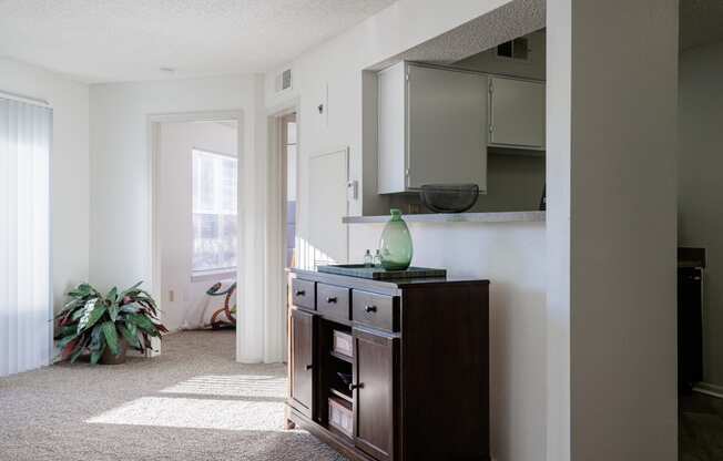 a living room with a dresser and a mirror on the wall