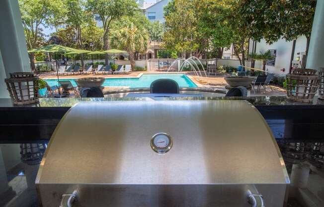 a grill with a swimming pool and trees in the background