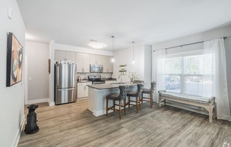 an open kitchen and dining area with a stainless steel refrigerator
