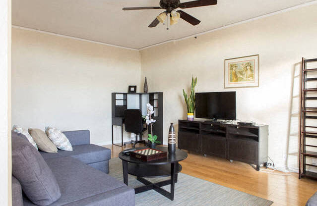 living room with ceiling fan and home office in the corner