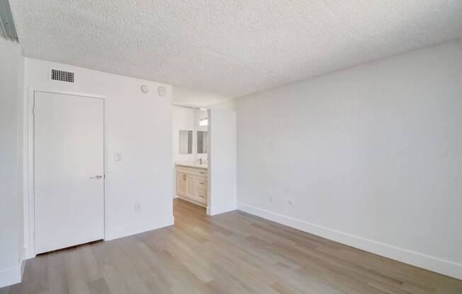 A white room with a wooden floor and a white door.