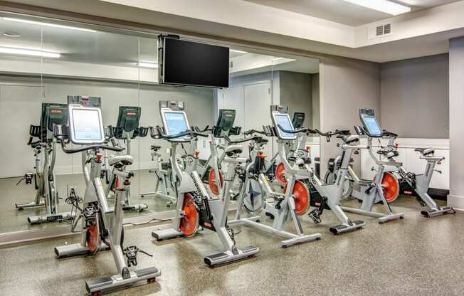 a room filled with lots of cardio equipment and a flat screen tv