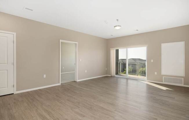 A large empty room with wooden flooring and white walls.