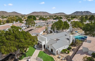 A large white building with a pool in the foreground and a mountain range in the background.