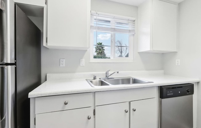 A kitchen with white cabinets and a window.