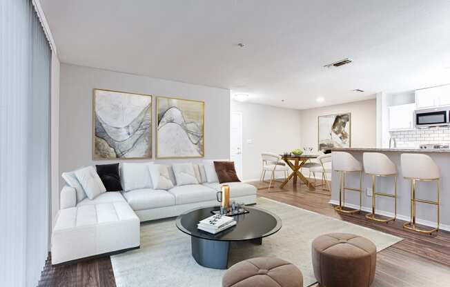 a living room with a white couch and coffee table and a kitchen with a bar