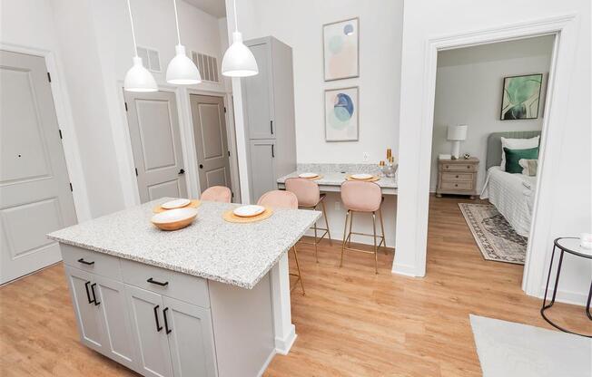 Kitchen island near a small dining nook with two chairs with access to the bedroom and entry way