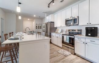 a large kitchen with white cabinets and stainless steel appliances