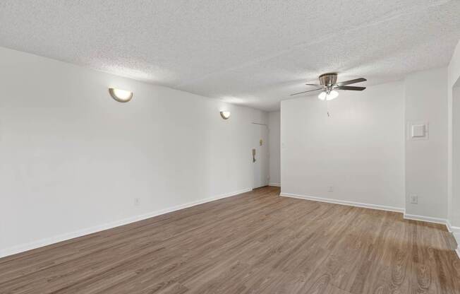 Empty room with wooden floor and ceiling fan.