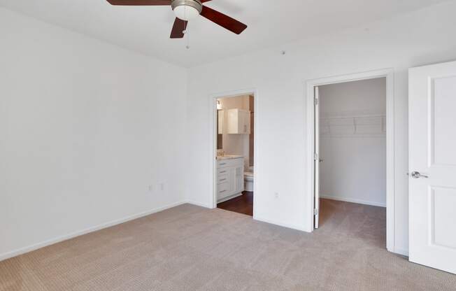 a living room with a ceiling fan and a door to a bathroom