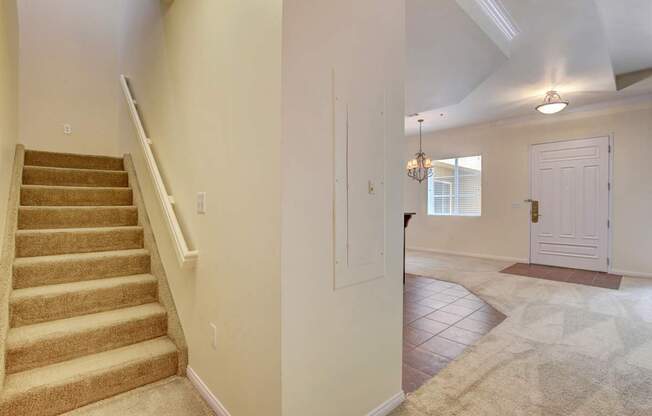 A hallway with a staircase and a rug on the floor.