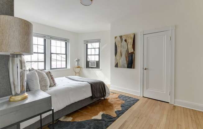 bedroom with bed, nightstands, large windows and hardwood floors at the dahlia apartments in washington dc