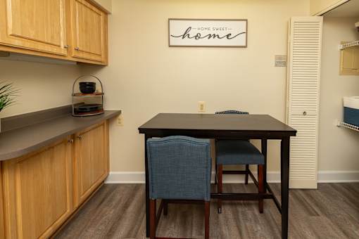 A kitchen with a table and chairs and a sign on the wall.