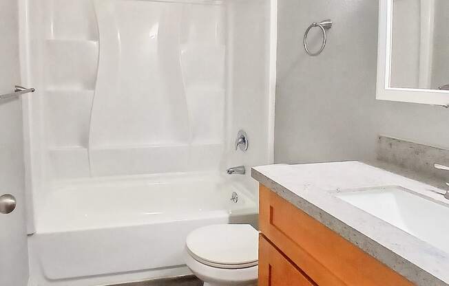 A white toilet sits in a bathroom next to a bathtub and a sink.