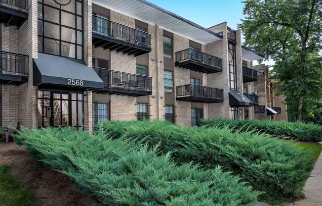 an exterior view of a brick apartment building with green plants