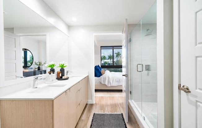 Spa-inspired bathroom design features clean lines, warm wood cabinetry, and glass-enclosed showers—bringing a calm, coastal feel to Modera Aventura homes.