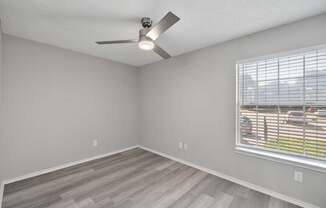 A room with a ceiling fan and a window with blinds.