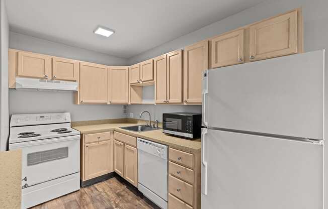 A kitchen with a white refrigerator, white oven, and wooden cabinets.