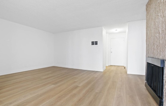 an empty living room with a fireplace and wooden floors