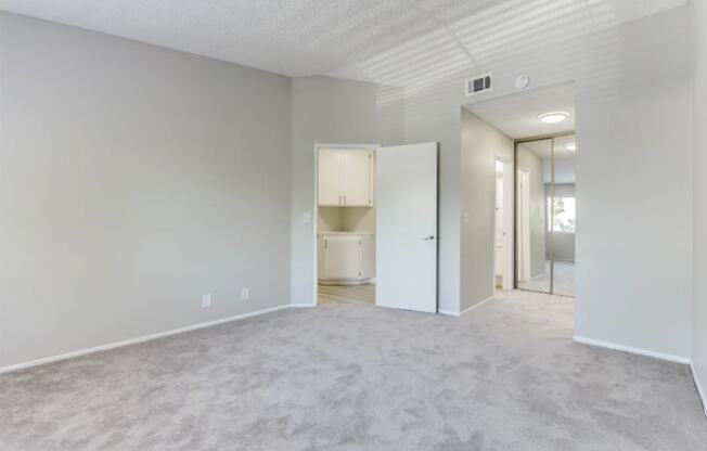 an empty bedroom with a closet and a bathroom in the background