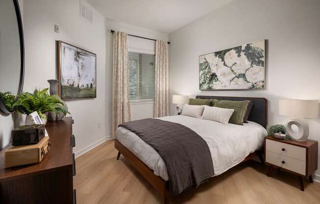 A bedroom with a large bed and a painting on the wall.