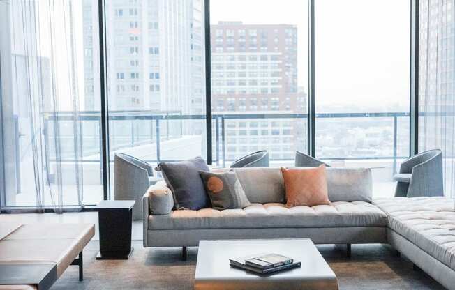 a living room with a couch and a table in front of windows at The Lively, Jersey City, NJ