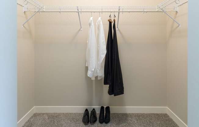 a walk in closet with a coat rack and a pair of shoes on the floor