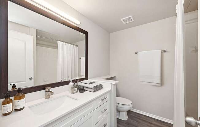 Model Bathroom with Wood-Style Flooring, White Cabinets & Shower/Tub at Allure North Dallas Apartments located in Dallas, TX.